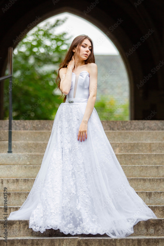 Beautiful girl wearing white wedding dress posing alone on the chapel stairs Beautiful girl wearing white wedding dress posing alone on the chapel stairs