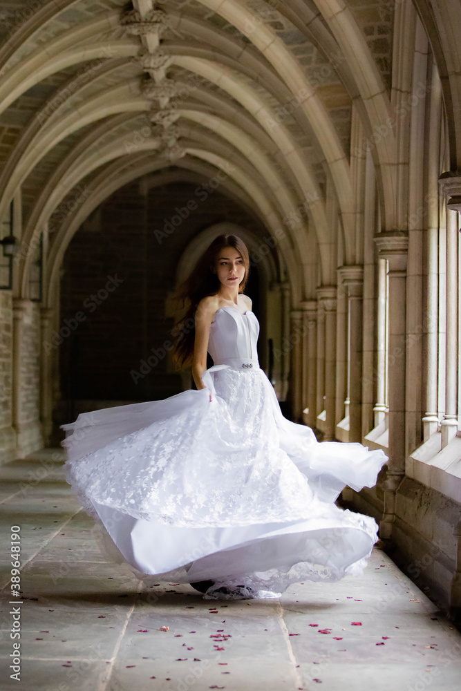 Beautiful girl wearing wedding dress spinning in the hall