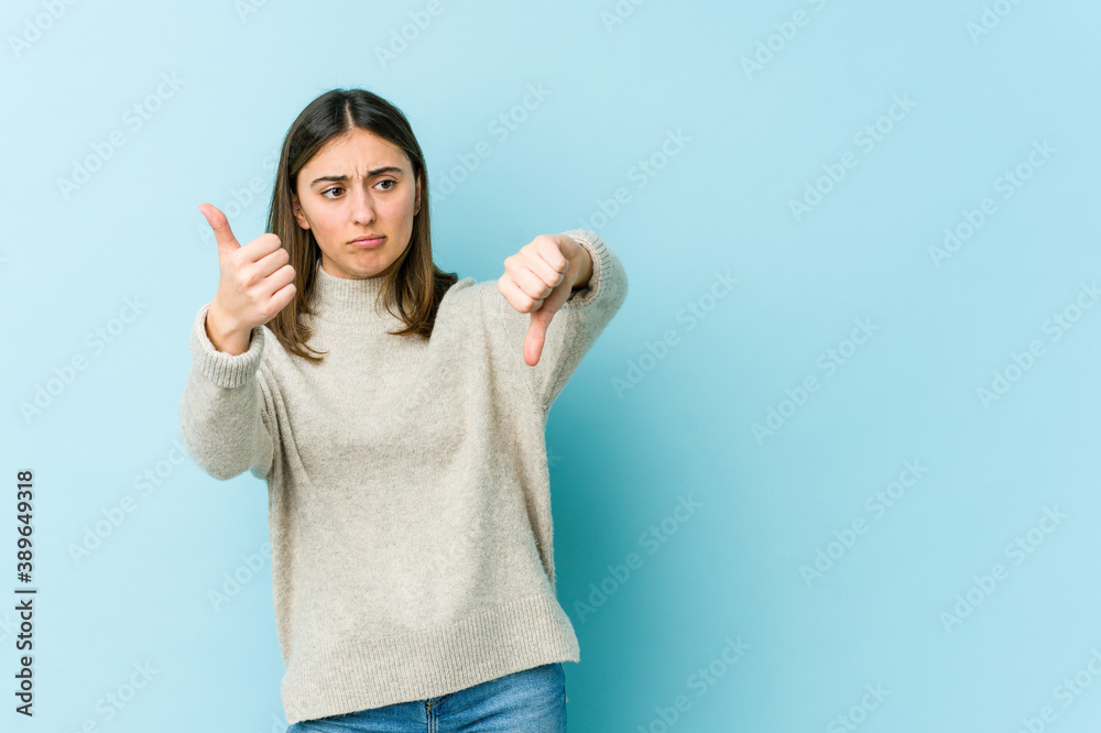 Young caucasian woman showing thumbs up and thumbs down, difficult choose concept