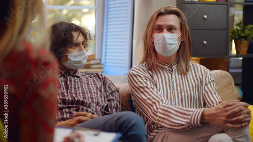 Two gay men wearing safety mask on conversation with family psychologist