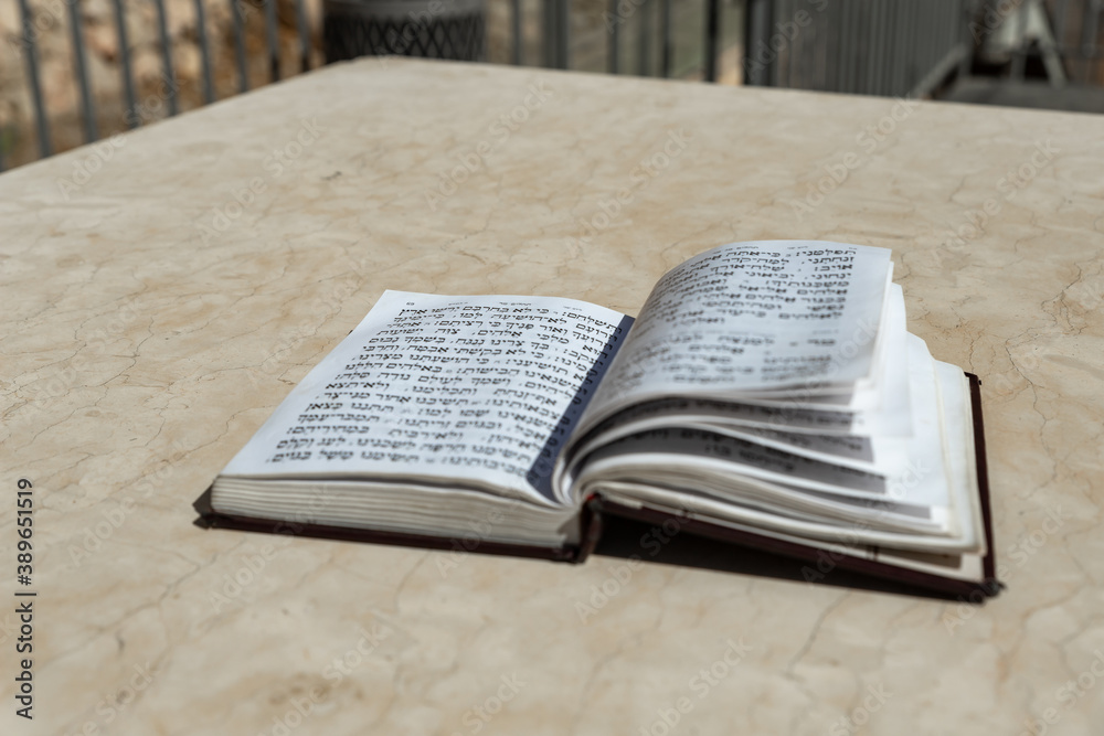Obraz premium The open holy book of Jews with the text of prayers in Hebrew - Tehelim, lies on a table near the Western Wall in the old city. of Jerusalem in Israel