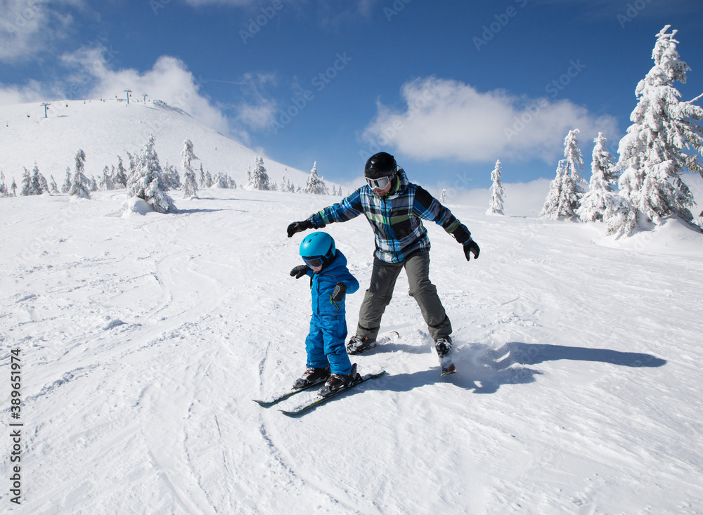 Happy little boy learning skiing with his daddy during winter holidays. Winter active walks with children. Seasonal joys, happy childhood. Frosty weather