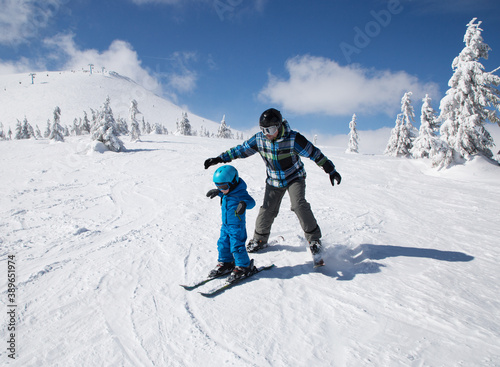 Happy little boy learning skiing with his daddy during winter holidays. Winter active walks with children. Seasonal joys, happy childhood. Frosty weather