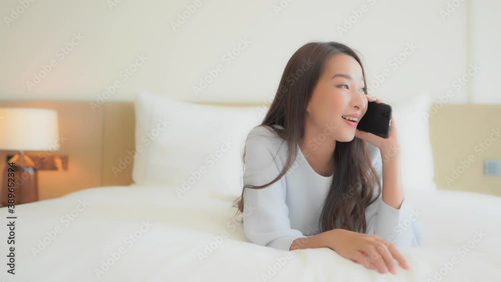A beautiful girl relaxing on her hotel suite bed, answers her smartphone recognizes the voice and smiles. Title space A beautiful girl relaxing on her hotel suite bed, answers her smartphone recognizes the voice and smiles. Title space