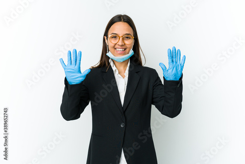 Young business latin woman wearing a mask to protect from covid isolated on white background showing number ten with hands.