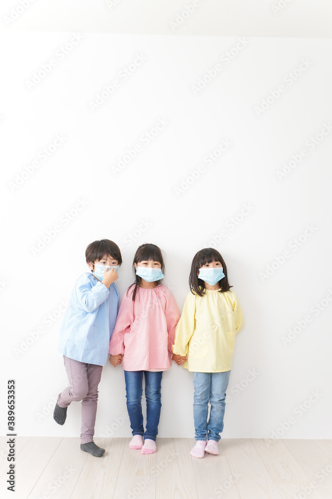 マスクをつけて手を繋ぐ幼稚園児