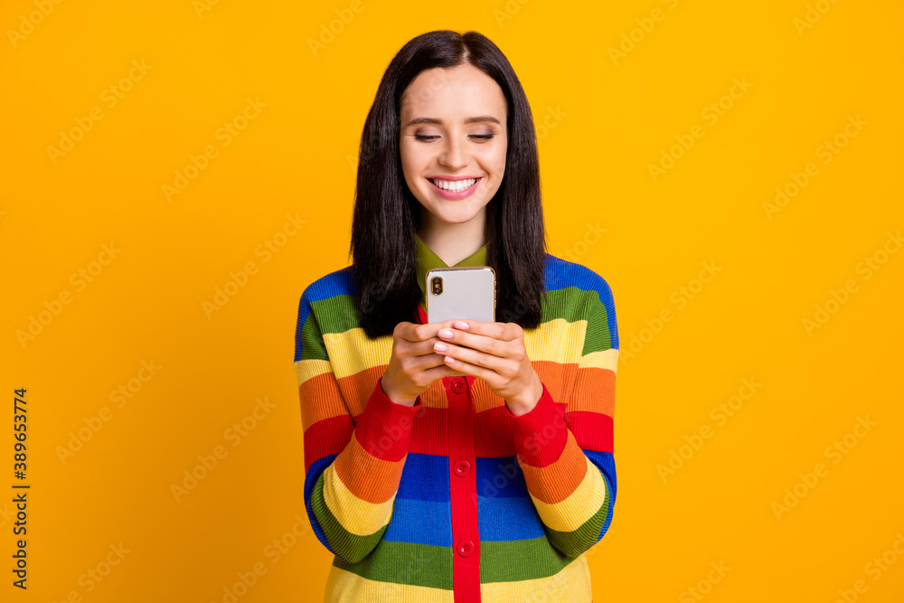 Photo of cheerful young girl smile chat text communicate cellphone mobile isolated over yellow color background Photo of cheerful young girl smile chat text communicate cellphone mobile isolated over yellow color background