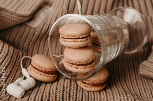 white headphones and caramel macaroons on a sweater. cozy autumn photography. photograph of food in brown tones. winter Playlist