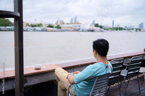 Man relaxing on a chair and enjoying by the river with coffee.