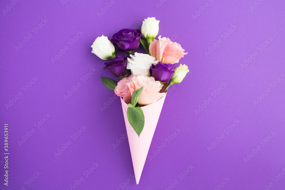 White, pink and violet flowers in a paper pink cone on the violet background White, pink and violet flowers in a paper pink cone on the violet background