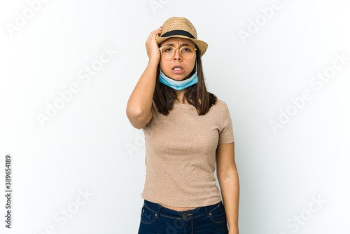 Young latin woman wearing hat and mask to protect from covid isolated on white background tired and very sleepy keeping hand on head.