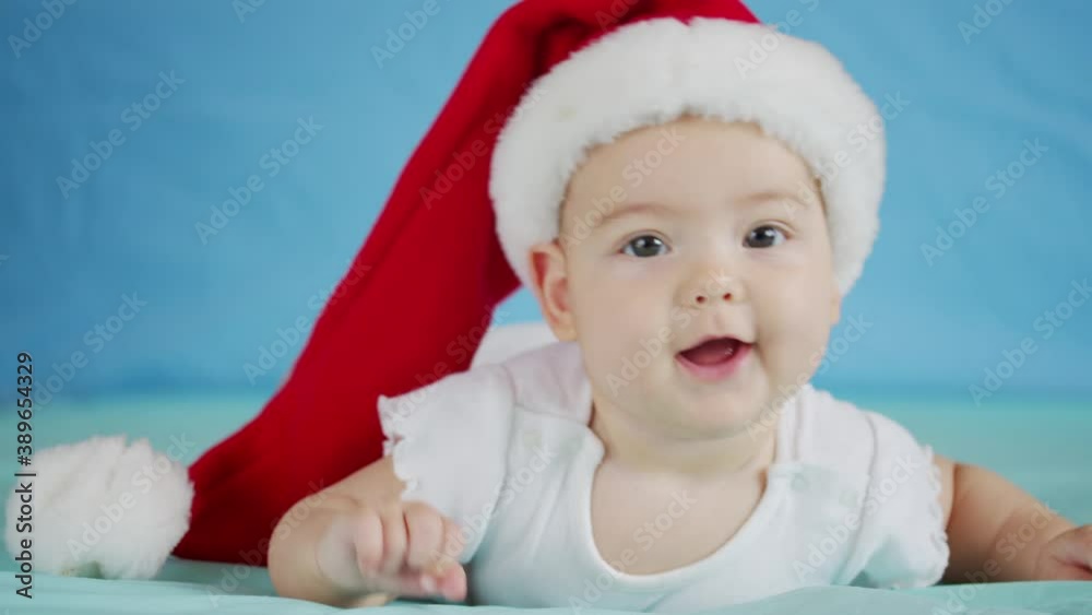 Merry Christmas and happy new year, childhood, holidays concept close-up. 3 month old newborn baby in Santa Claus hat on his tummy crawls. Merry Christmas and happy new year, childhood, holidays concept close-up. 3 month old newborn baby in Santa Claus hat on his tummy crawls.