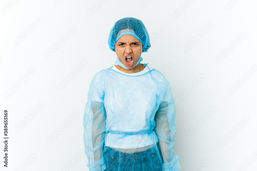 Young surgeon latin woman isolated on white background screaming very angry and aggressive. Young surgeon latin woman isolated on white background screaming very angry and aggressive.