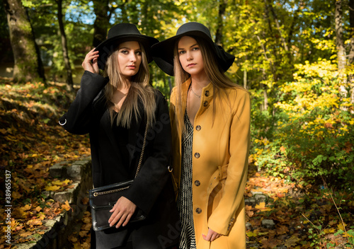 sesja fotograficzna w parku jesień dwie piękne białe kobiety dziewczyny w kapeluszach photo