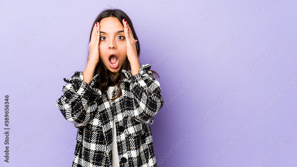 Young mixed race hispanic woman isolated having fun covering half of face with palm.