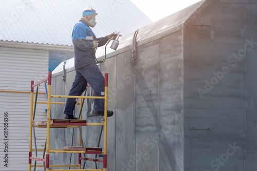 Wallpaper Mural Industrial work. Priming of metal products from the compressor gun. A worker in overalls and a respirator paints the body of a truck trailer or a metal car. Torontodigital.ca