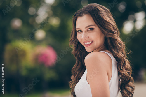 Profile photo of pretty cute young woman smiling have long curly brunette hair walking around wear white top outdoors