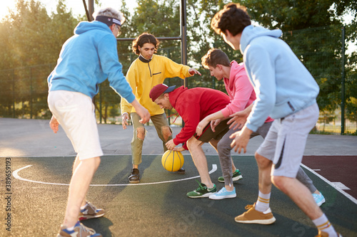 young caucasian boys have fantastic active basketball game, handsome guys in casual clothes gathered to hold competition