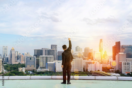 Businessman standing on a roof and looking at city, Raise your hands to express your joy in your accomplishments.