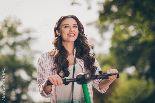 Photo of adorable optimistic brunette hair young lady drive segway wear striped shirt enjoy day in park outside