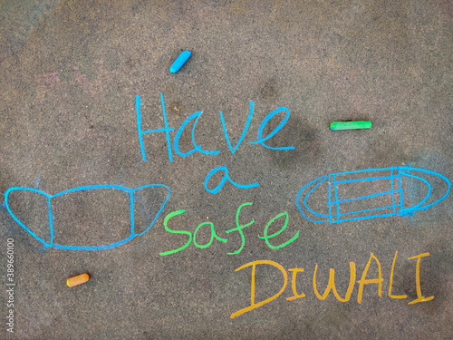 The inscription text on the grey board,Have a safe diwali with surgical mask. Using color chalk pieces.