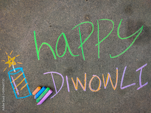 The inscription text on the grey board,Happy diwali with fire crackers. Using color chalk pieces.
