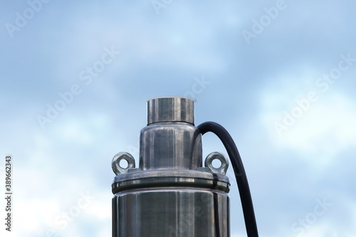 Screw pump for wells against on the background blue sky. Submersible borehole pump top with black cable.