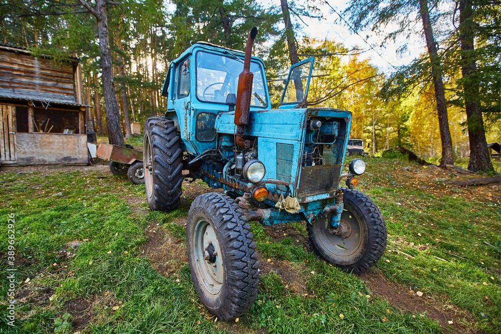 An old blue tractor stands in a farmyard An old blue tractor stands in a farmyard