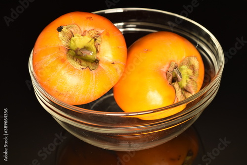 Ripe juicy organic persimmon, close-up, on a black background.