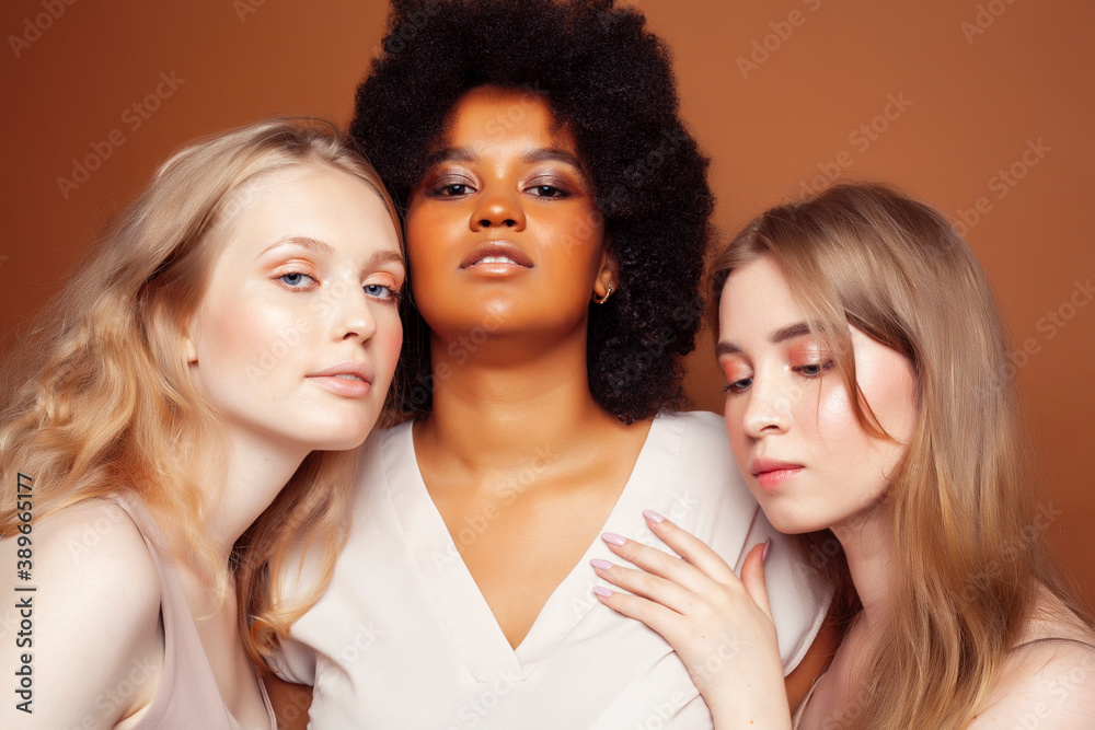 young pretty caucasian, afro, scandinavian woman posing cheerful together on brown background, lifestyle diverse nationality people concept young pretty caucasian, afro, scandinavian woman posing cheerful together on brown background, lifestyle diverse nationality people concept