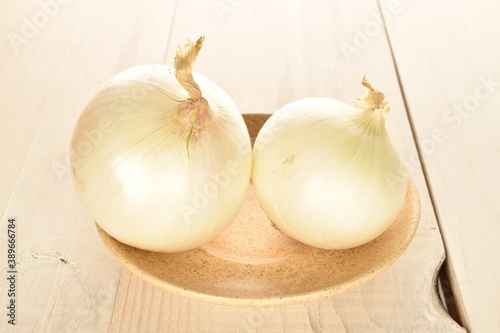 Ripe white organic onions, close-up, on a white wooden table.
