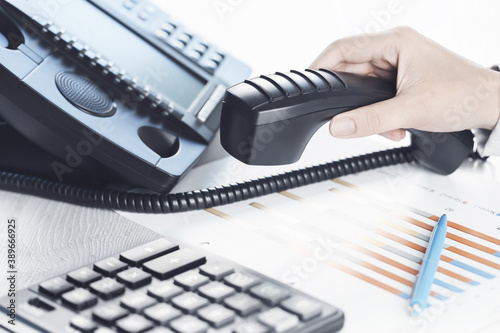 business communications. Finance graphs. Using voip phone. office, close up of hand with receiver. Conference call, contact us or financial advice. IP telephony, Telemarketing. Help desk call centre