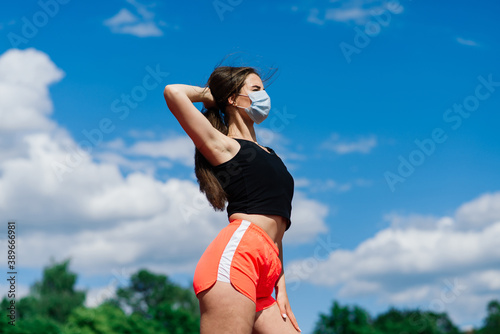 Young fit female in sportswear and protective mask for coronavirus on track during outdoor workout © Ivan Zelenin