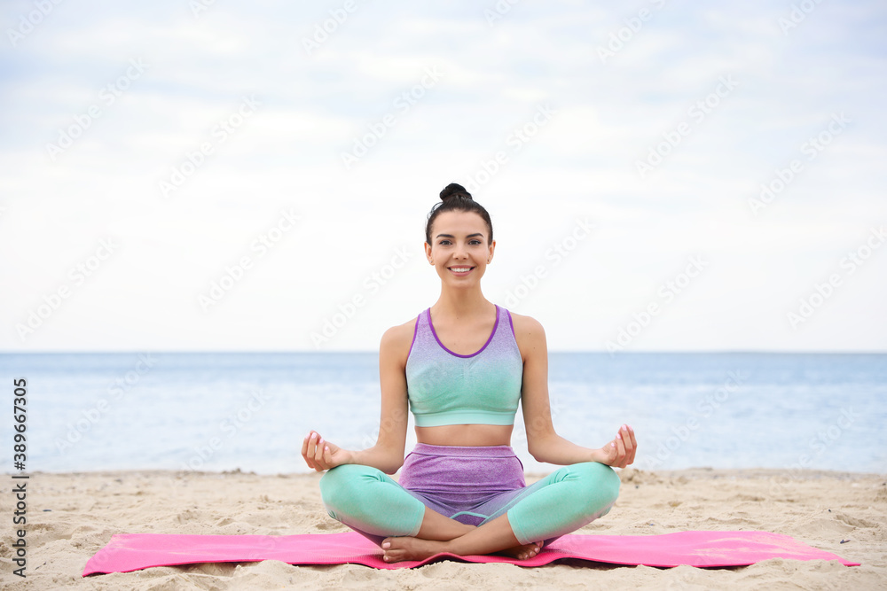 Young woman practicing yoga on beach. Body training