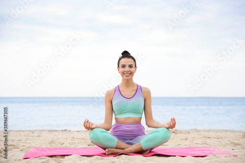 Young woman practicing yoga on beach. Body training