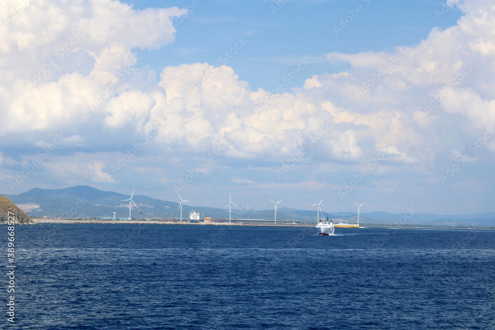 La costa di Piombino in Toscana con pale eoliche traghetti cielo e nuvole