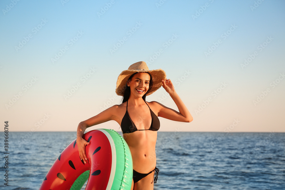 Beautiful young woman in black stylish bikini with inflatable ring on beach Beautiful young woman in black stylish bikini with inflatable ring on beach