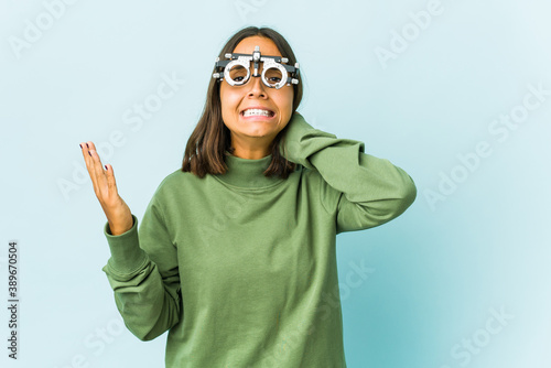 Young oculist latin woman over isolated background