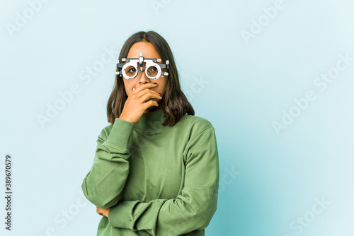 Young oculist latin woman over isolated background