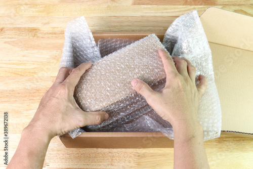 hand of man hold Bubbles covering the box by bubble wrap for protection product photo