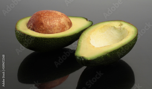 Slices of fresh avocados reflected on a black background. Side view