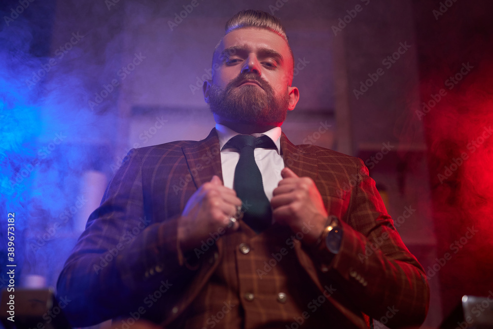 handsome young bearded man in a tuxedo sitting in dark room in fashionable clothing for the festive evening handsome young bearded man in a tuxedo sitting in dark room in fashionable clothing for the festive evening