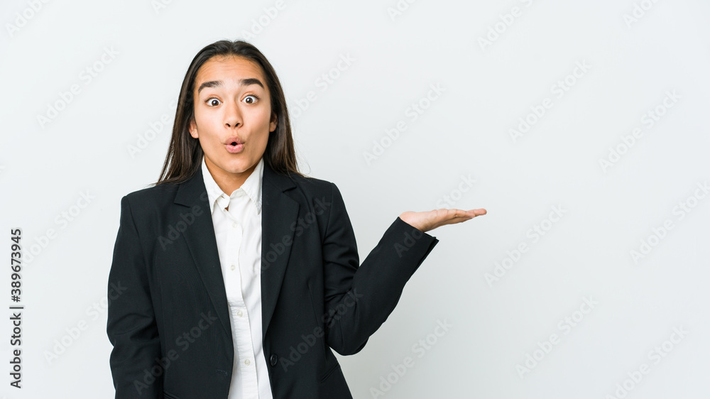 Young asian bussines woman isolated on white background impressed holding copy space on palm. Young asian bussines woman isolated on white background impressed holding copy space on palm.