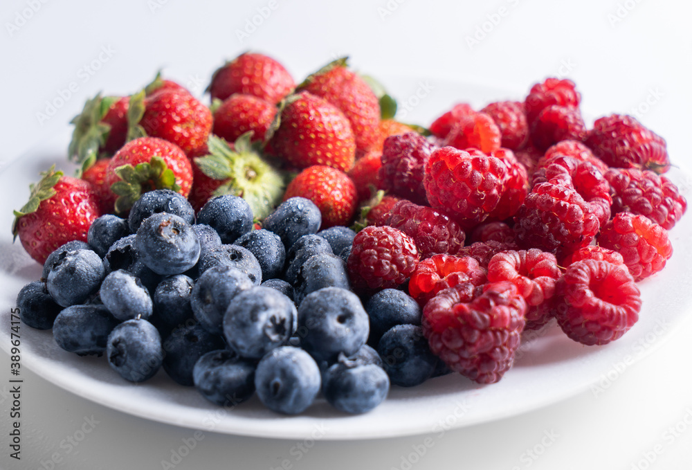 Fresh delicious berries Strawberries, blueberries and raspberries close-up in a white plate Fresh delicious berries Strawberries, blueberries and raspberries close-up in a white plate