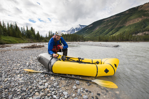 Paddler inflates yellow packraft next to North Saskatchewan River. photo