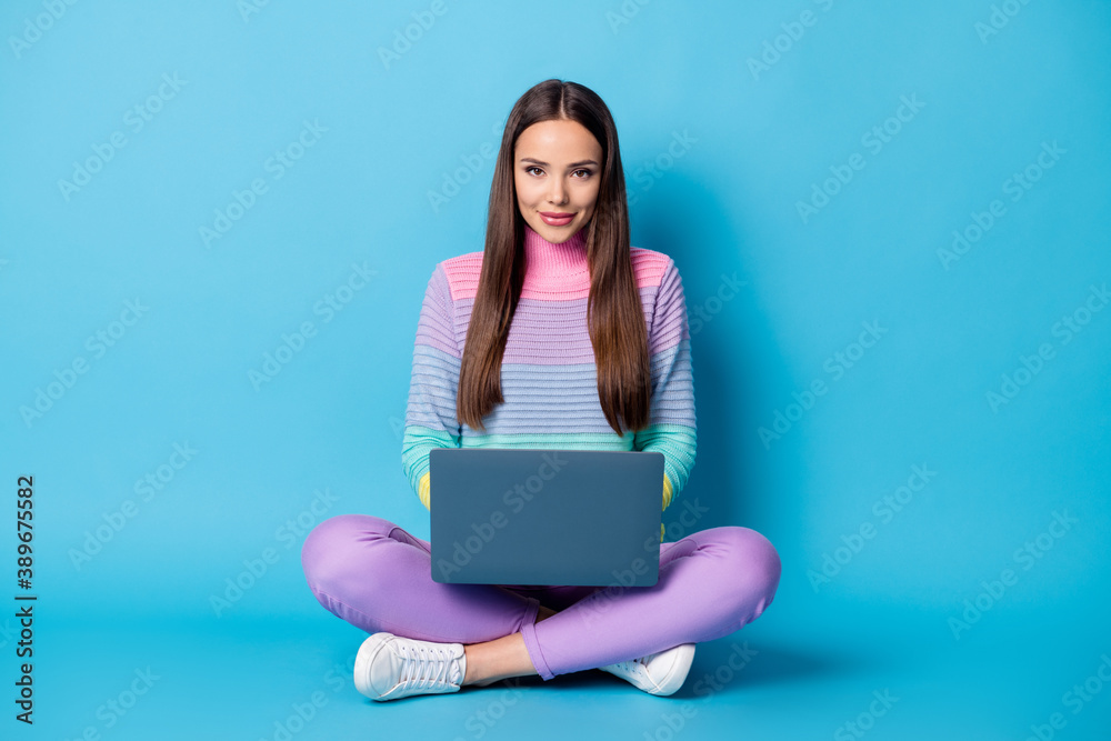Portrait of cute cheery girl sitting lotus position crossed legs using laptop web search isolated on bright blue color background Portrait of cute cheery girl sitting lotus position crossed legs using laptop web search isolated on bright blue color background