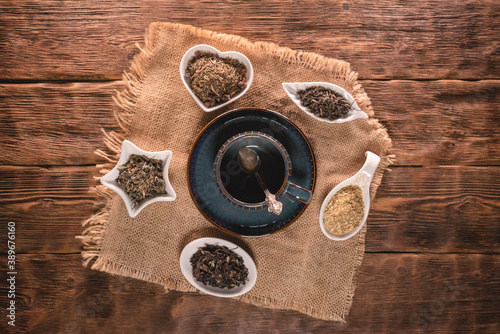 Various kinds of dried tea leaves and empty tea cup on the old brown wooden table background.