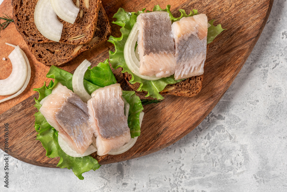 Sandwich with salted herring, rye bread, onions, and lettuce close-up. Scandinavian food. Sandwich with salted herring, rye bread, onions, and lettuce close-up. Scandinavian food.