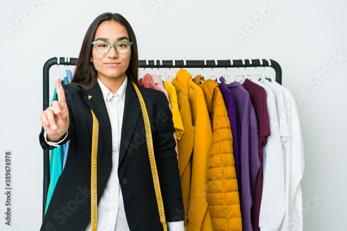 Young asian designer woman isolated on white background showing number one with finger.