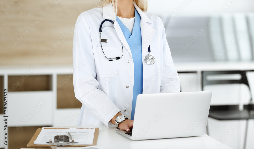 Unknown female physician using laptop computer, close-up. Woman-doctor at work in clinic. Medicine concept Unknown female physician using laptop computer, close-up. Woman-doctor at work in clinic. Medicine concept